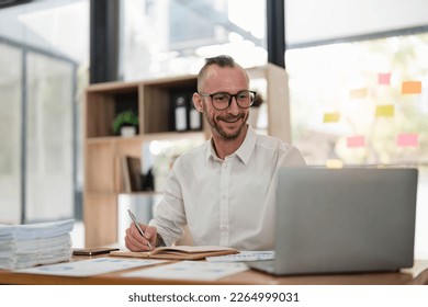 Businessman using laptop computer in office. Happy middle aged man, entrepreneur, small business owner working online. - Shutterstock ID 2264999031