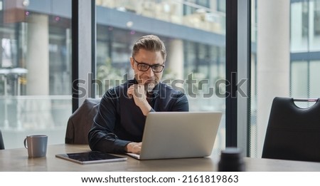 Businessman using laptop computer in office. Happy middle aged man, entrepreneur, small business owner working online.
