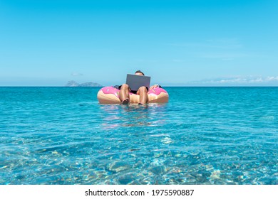 Businessman Using Laptop Computer On An Inflatable Donut In The Sea. Summer Vacation Concept.