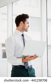 Businessman using laptop and taking notes in office
