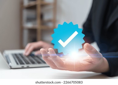 Businessman using laptop with verification account blue tick checkmark concept, verification account on social media platform, subscription status, eliminate bots, spam.