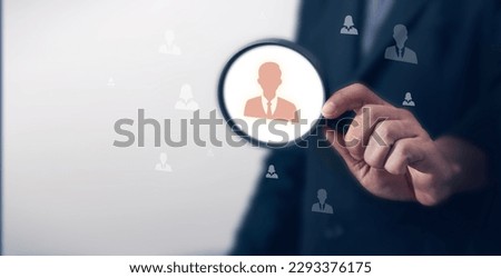 Businessman using magnifying glass to search human virtual icons for leadership development, recruitment and prospecting concept, HRM or Human Resource Management. Selection. Selection.
