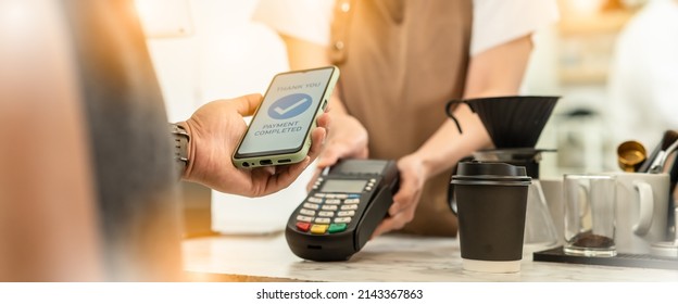 Businessman using mobile payment technology to pay bill in coffee shop.man with manicure holding smartphone and using contactless payment system.new normal lifestyle concept - Shutterstock ID 2143367863