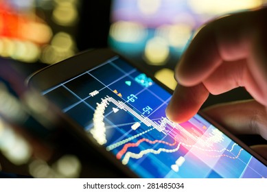 A businessman using a mobile phone to check stock market data.