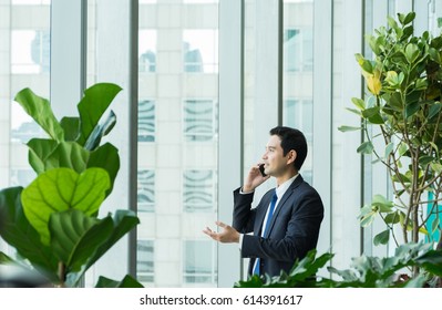 Businessman using mobile phone near office window at receptions area,Negotiation concept - Powered by Shutterstock