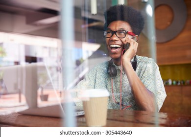 Businessman Using Phone Working On Laptop In Coffee Shop