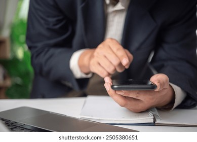 Businessman using a smartphone in an office setting, representing digital finance and communication. Suitable for fintech services, mobile banking apps - Powered by Shutterstock