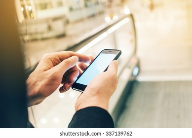 Businessman using smartphone on the escalator, with flare effect - Powered by Shutterstock