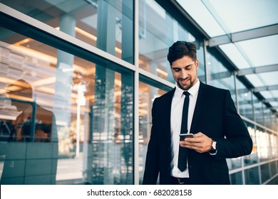 Businessman Using Smartphone And Smiling At Airport. Young Business Executive With Mobile Phone At Airport.