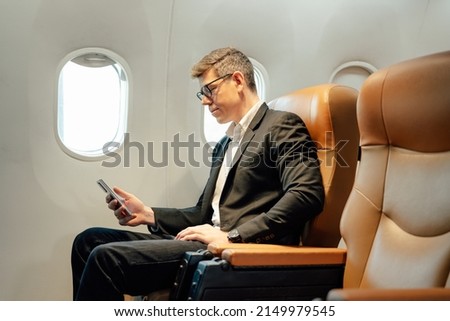 Businessman using smartphone while sitting in airplane, Traveling and technology. Flying at first class.