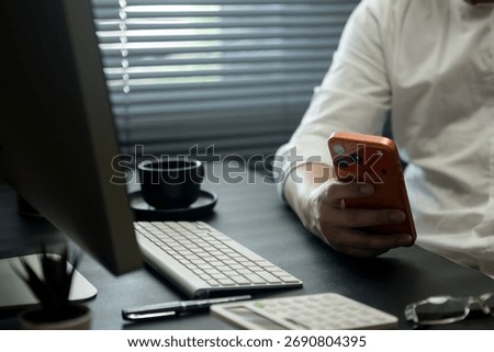 Businessman is using a smartphone while sitting at his desk