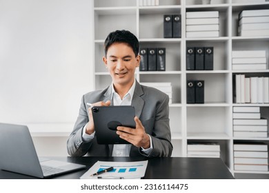 Businessman using a tablet to analysis graph company financial in office.