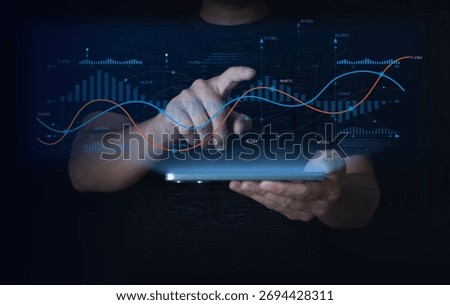  Businessman using tablet to analyze digital financial data with glowing line and bar graphs. Concept of big data analytics, fintech, technology, and futuristic business performance visualization.