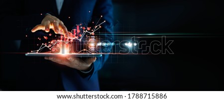 Businessman using tablet analyzing sales data and economic growth graph chart and block chain technology on global network on dark background.