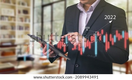 Businessman using tablet analyzing sales, financial data and economic growth graph chart to predict 2022 fiscal year. Business strategy, Digital marketing, Big Data concept.