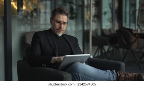 Businessman using tablet computer in office. Serious middle aged man in business casual, Entrepreneur working online, reading finance report, thinking. .