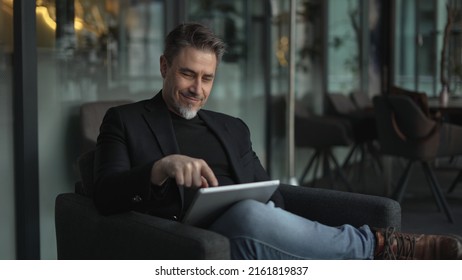 Businessman using tablet computer in office. Happy middle aged man in business casual, Entrepreneur working online, reading finance report, thinking. - Shutterstock ID 2161819837