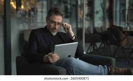 Businessman using tablet computer in office. Middle aged man in business casual, Entrepreneur working online, reading finance report, thinking.  .