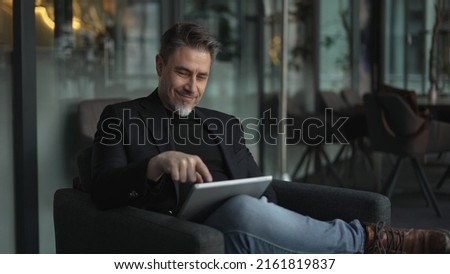 Businessman using tablet computer in office. Happy middle aged man in business casual, Entrepreneur working online, reading finance report, thinking.