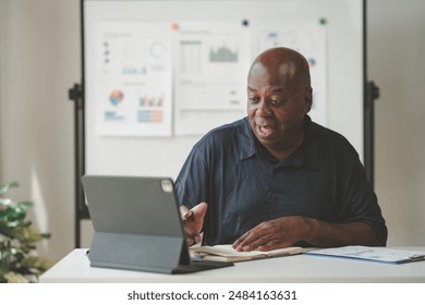 Businessman using a tablet during a meeting, analyzing data charts and graphs displayed on a whiteboard. Professional workspace environment. - Powered by Shutterstock