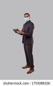 Businessman Using Tablet Wearing Medical Mask Isolated. Indian Business Man Standing Full Length With Tablet In Hands