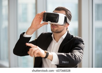 Businessman using technology of augmented reality in daily office work. Man ceo wearing virtual reality glasses, pointing at the air. Office worker in electronics 3d goggles interacts with simulation - Powered by Shutterstock