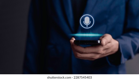 businessman using utilizes his smartphone as an AI assistant, effectively issuing voice commands through its microphone symbol, enhancing productivity with cutting-edge technology. - Powered by Shutterstock