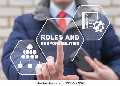 Businessman using virtual touchscreen presses the inscription: ROLES AND RESPONSIBILITIES. Roles and Responsibilities Business Organization Motivation Concept.