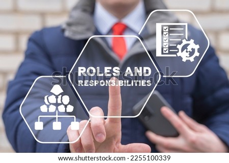 Businessman using virtual touchscreen presses the inscription: ROLES AND RESPONSIBILITIES. Roles and Responsibilities Business Organization Motivation Concept.