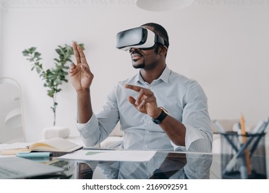 Businessman in vr headset clicks virtual buttons. Freelancer is working on design project. African american man in futuristic vr headset at home. Modern digital technology for business and creativity. - Powered by Shutterstock