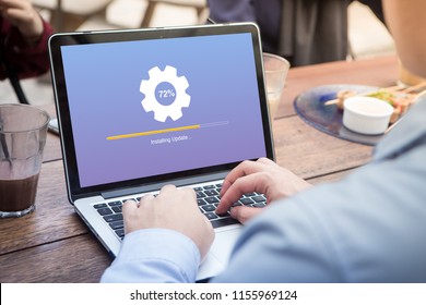 Businessman waiting for installing update process with gearbox percentage progress and loading bar on laptop / computer at the outdoor cafe