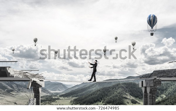 Businessman walking blindfolded\
on rope above huge gap in bridge as symbol of hidden threats and\
risks. Flying balloons and nature view on background. 3D\
rendering.