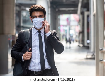 Businessman walking in city with very small amount of people during covid-19 outbreak make phone call and wearing white mask - Powered by Shutterstock