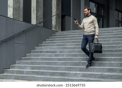 Businessman walking down grey concrete steps using smartphone, dressed in smart casual outfit, holding black leather briefcase. Image represents professional urban lifestyle, confidence, communication - Powered by Shutterstock