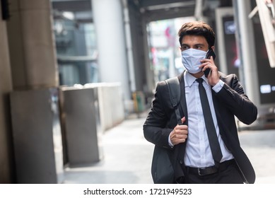 Businessman walking in an empty city during covid-19 outbreak make phone call and wearing white mask - Powered by Shutterstock