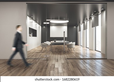 Businessman Walking In Modern Conference Room With Blank Tv Screen On Wall. Workplace And Corporate Concept.