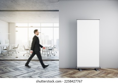 Businessman walking in modern glass office interior with empty mock up banner on wall, wooden flooring, furniture, window with city view and other objects - Shutterstock ID 2258427767