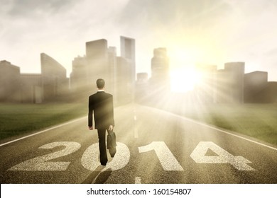 Businessman walking to the New Year 2014 with cityscape background