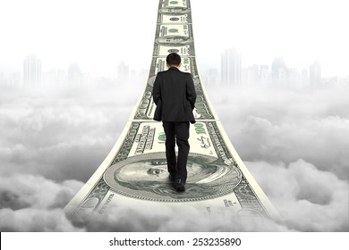 Businessman walking on the money stairs with gray cityscape cloudscape background - Powered by Shutterstock