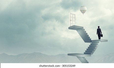 Businessman walking up staircase to door in sky