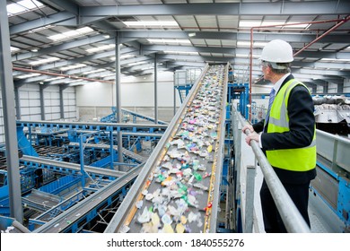 Businessman watching plastic on conveyor belt in recycling plant - Powered by Shutterstock