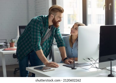 Businessman watching something on computer of his female colleague during work at office. Concept of business team and cooperation. Idea of business lifestyle. Young smiling caucasian man and woman - Powered by Shutterstock