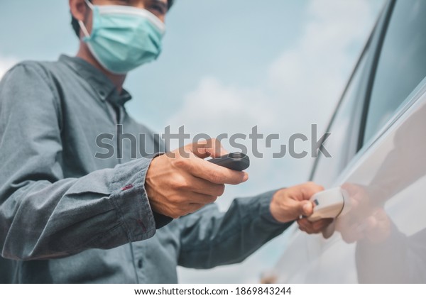 Businessman\
wear face mask holding key opening car\
door