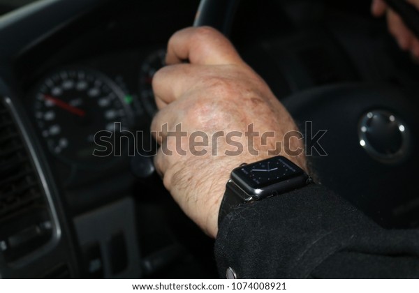 Businessman wearing black smart watch and black\
long sleeve shirt driving\
vehicle