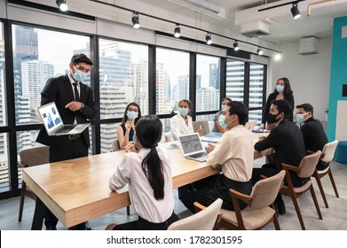 Businessman Wearing Face Mask With Presentation Of Business Plan On Laptop, Corporate Business Meeting In Modern Office While Pandemic Of Virus