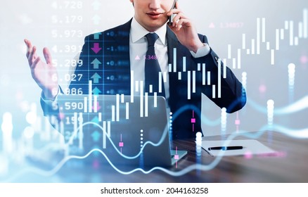 Businessman Wearing Formal Suit Is Having Video Conference Call On Smartphone. Office Workplace With Laptop And Paper In The Background. Financial Chart And Graph In The Foreground. Concept Of Trading