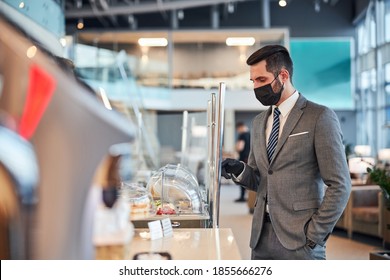 Businessman Wearing A Hospital Mask And Selecting A Dish On A Showcase Of A Snack-bar Of A Waiting Room