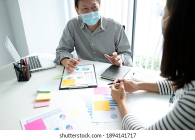 businessman wearing a mask explaining about the business marketing operation to an assistant or staff team  graph on the table note post on the wall in the background. - Powered by Shutterstock