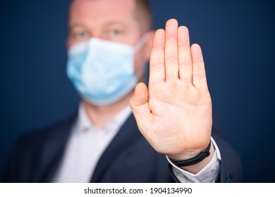 Businessman wearing medical mask showing stop sign with hand.