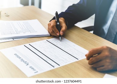 Businessman wearing suit signing the document in office.